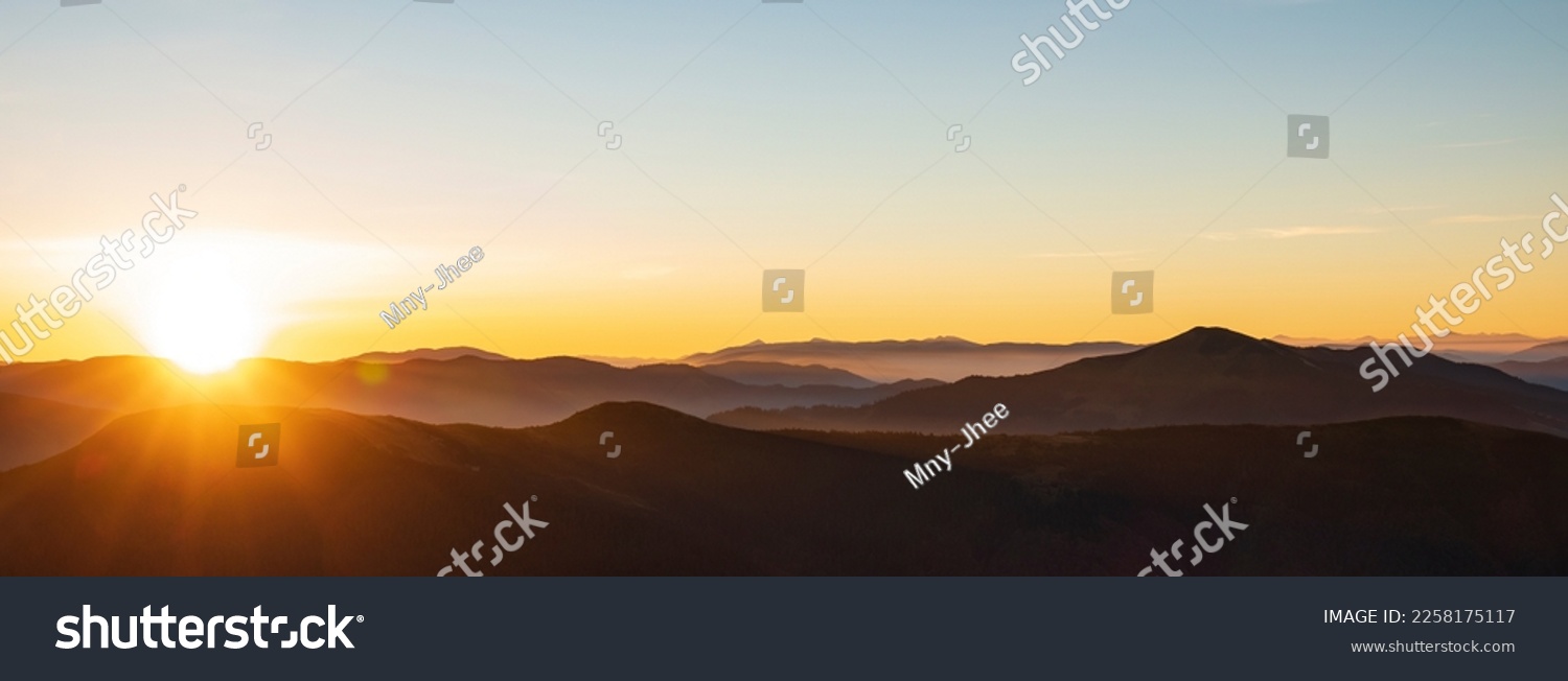 Mountain sunrise header. Mountain silhouettes and rays of the rising sun #2258175117