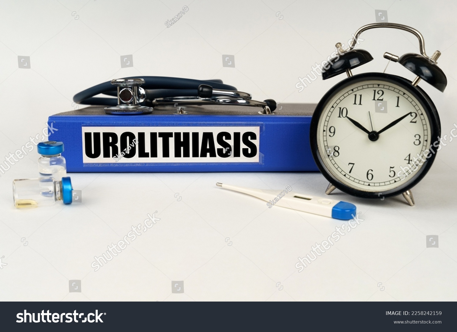 Medical concept. On a white surface, a thermometer, ampoules, a stethoscope, an alarm clock and a folder with the inscription - Urolithiasis #2258242159