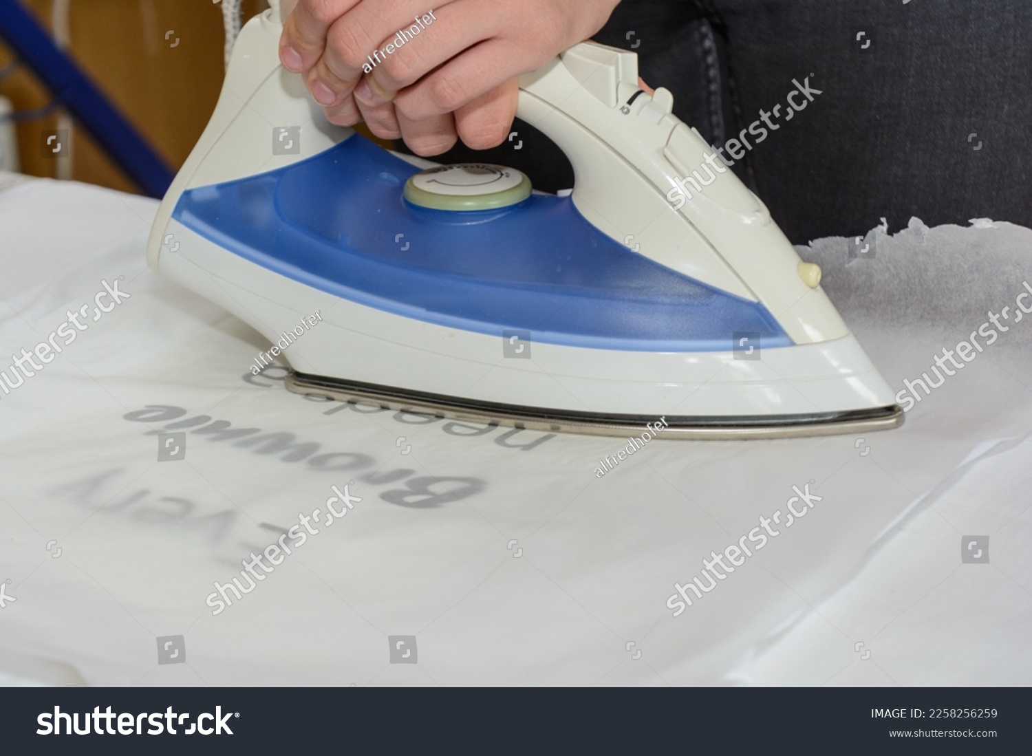 Person ironing an ironing sheet on t-shirt - closeup #2258256259