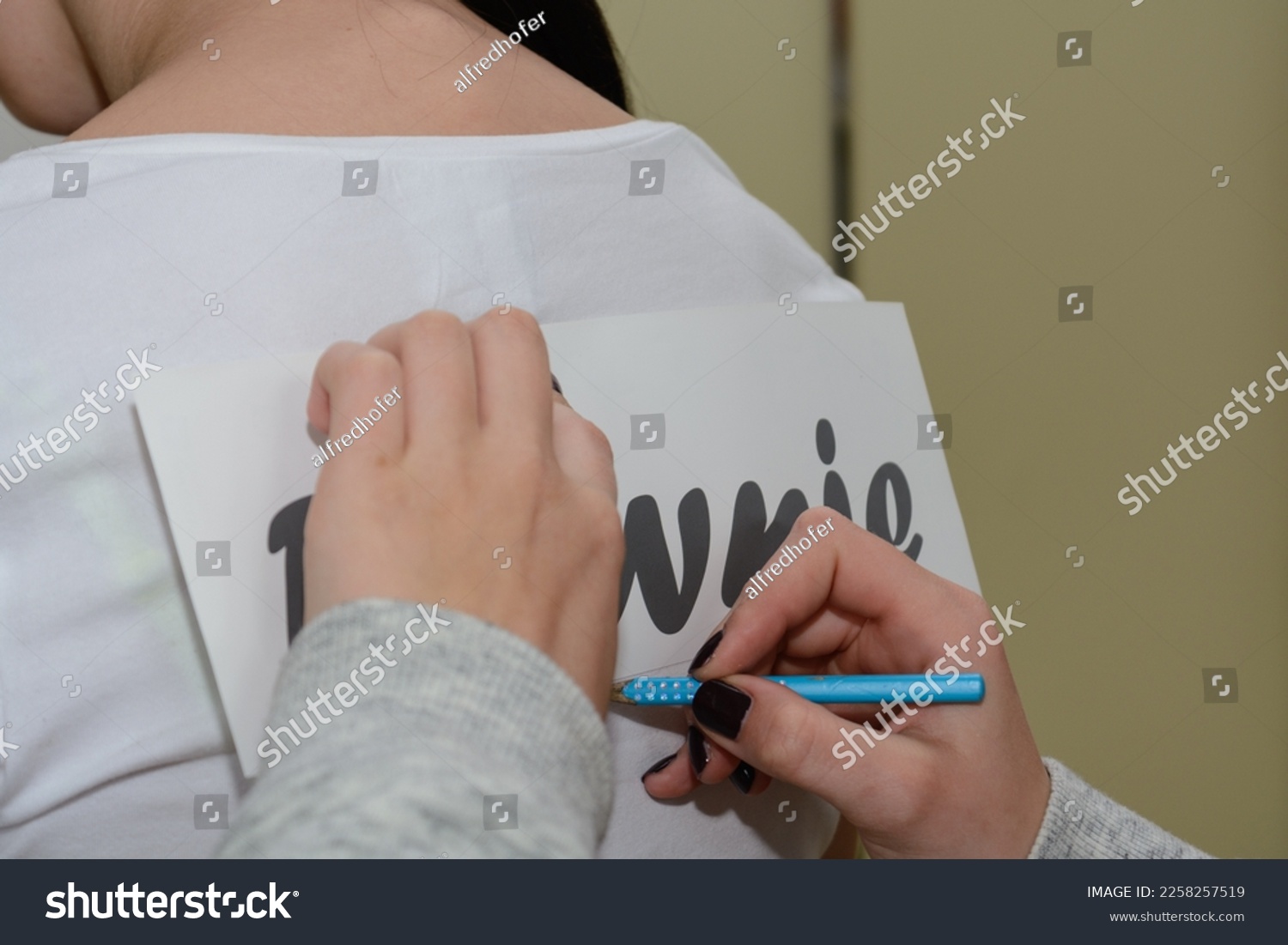 Person prepares text for foli print on a t-shirt #2258257519