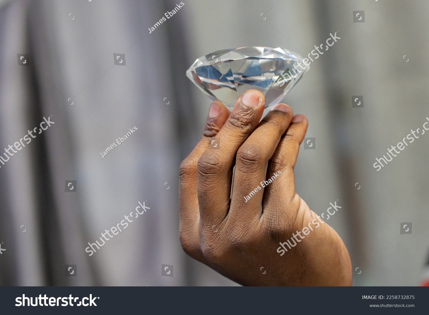 Focus on foreground of fingers holding a diamond. #2258732875
