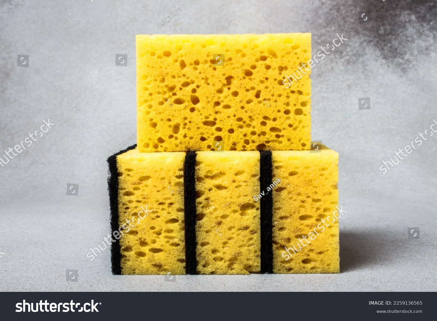 A stack of yellow dishwashing sponges close-up on a neutral gray background. Gentle dishwashing. House cleaning. #2259136565