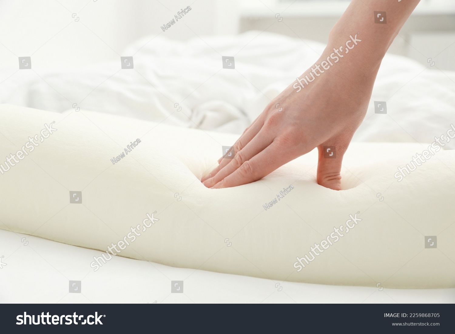Woman touching orthopedic memory foam pillow on bed, closeup. Space for text #2259868705
