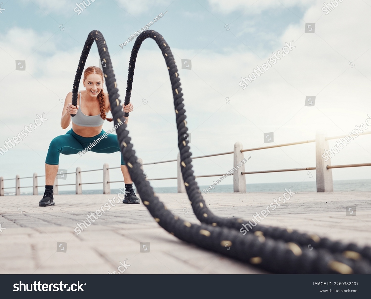 Fitness, woman and battle rope at the beach for intense arm workout, training or exercise in Cape Town. Active female exercising with ropes for cardio, muscle endurance or power in the outdoors #2260382407
