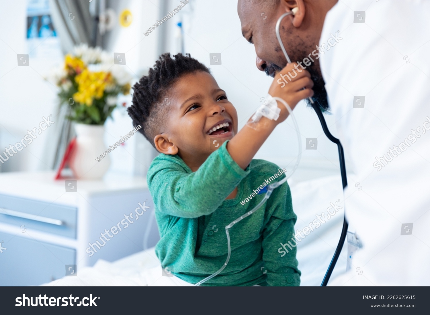 Laughing african american boy patient taking male doctor's stethoscope in hospital. Hospital, medical and healthcare services. #2262625615