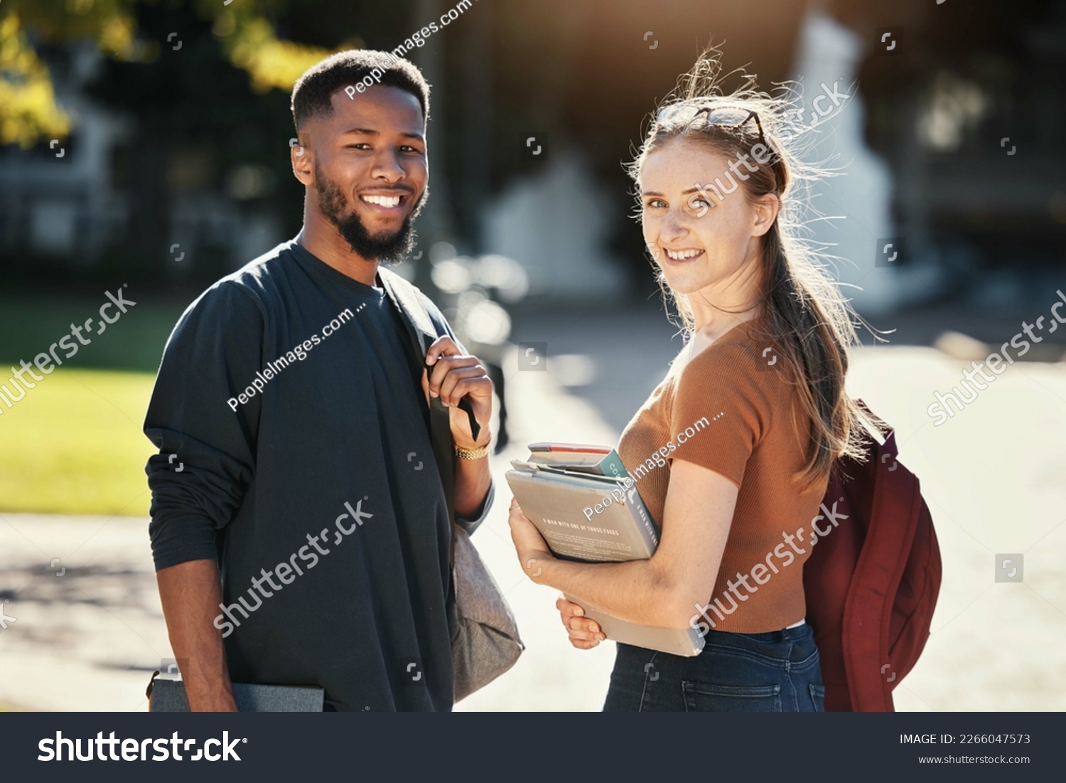 Students, couple or university friends walking together with books for education and learning on campus with scholarship. Portrait of an interracial man and woman together on college or school ground #2266047573