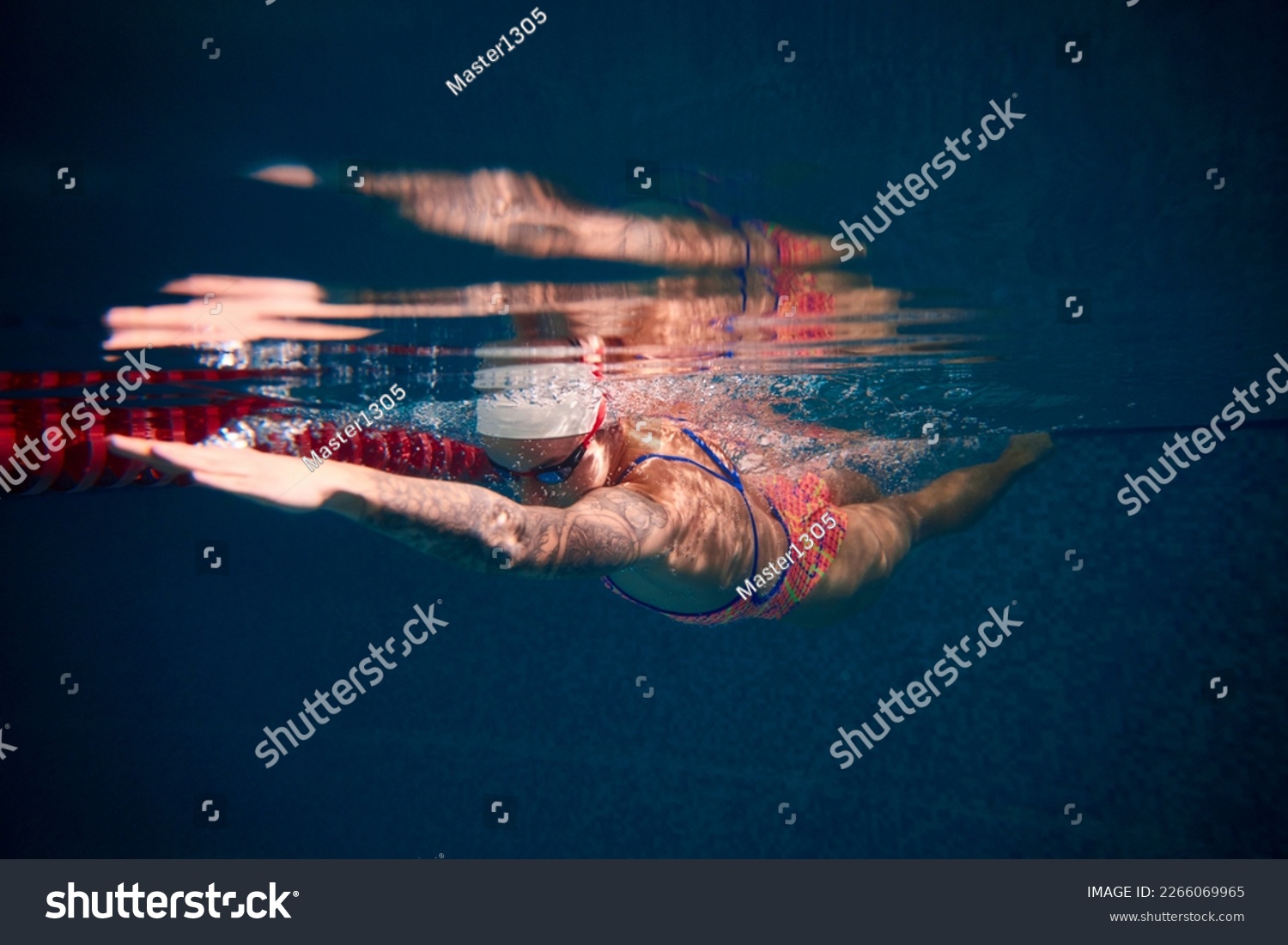 Growing speed and strength. Young woman, professional swimmer in goggles and cap training in swimming pool. Underwater view. Concept of sport, endurance, competition, energy, healthy lifestyle #2266069965