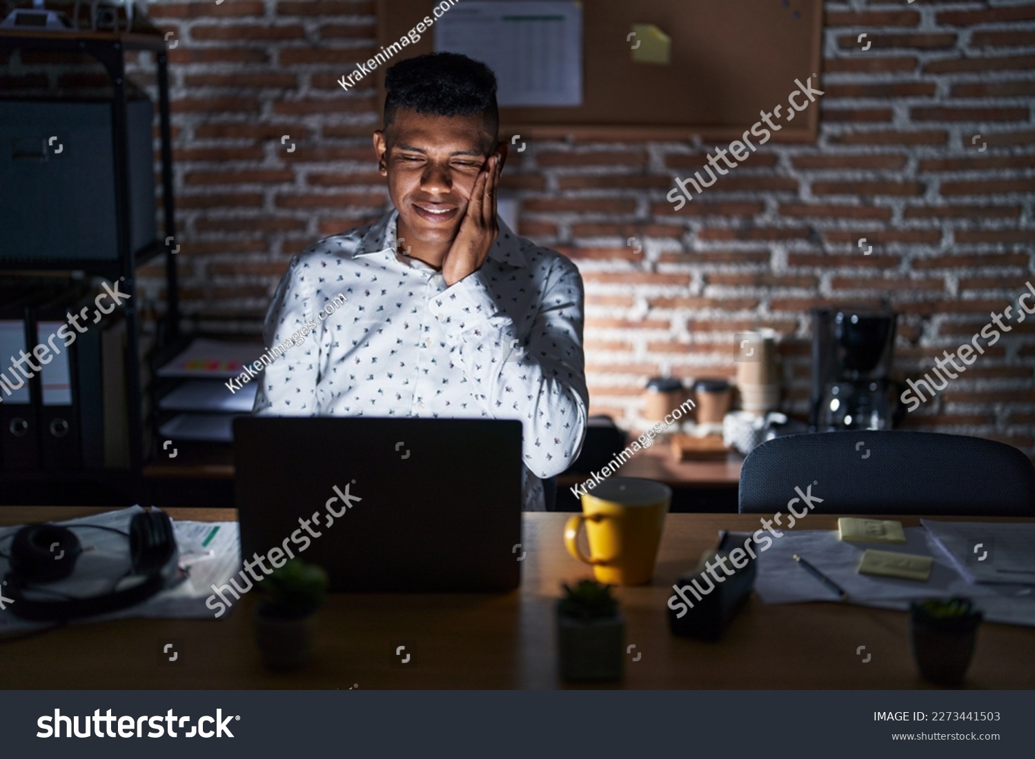 Young hispanic man working at the office at night touching mouth with hand with painful expression because of toothache or dental illness on teeth. dentist  #2273441503