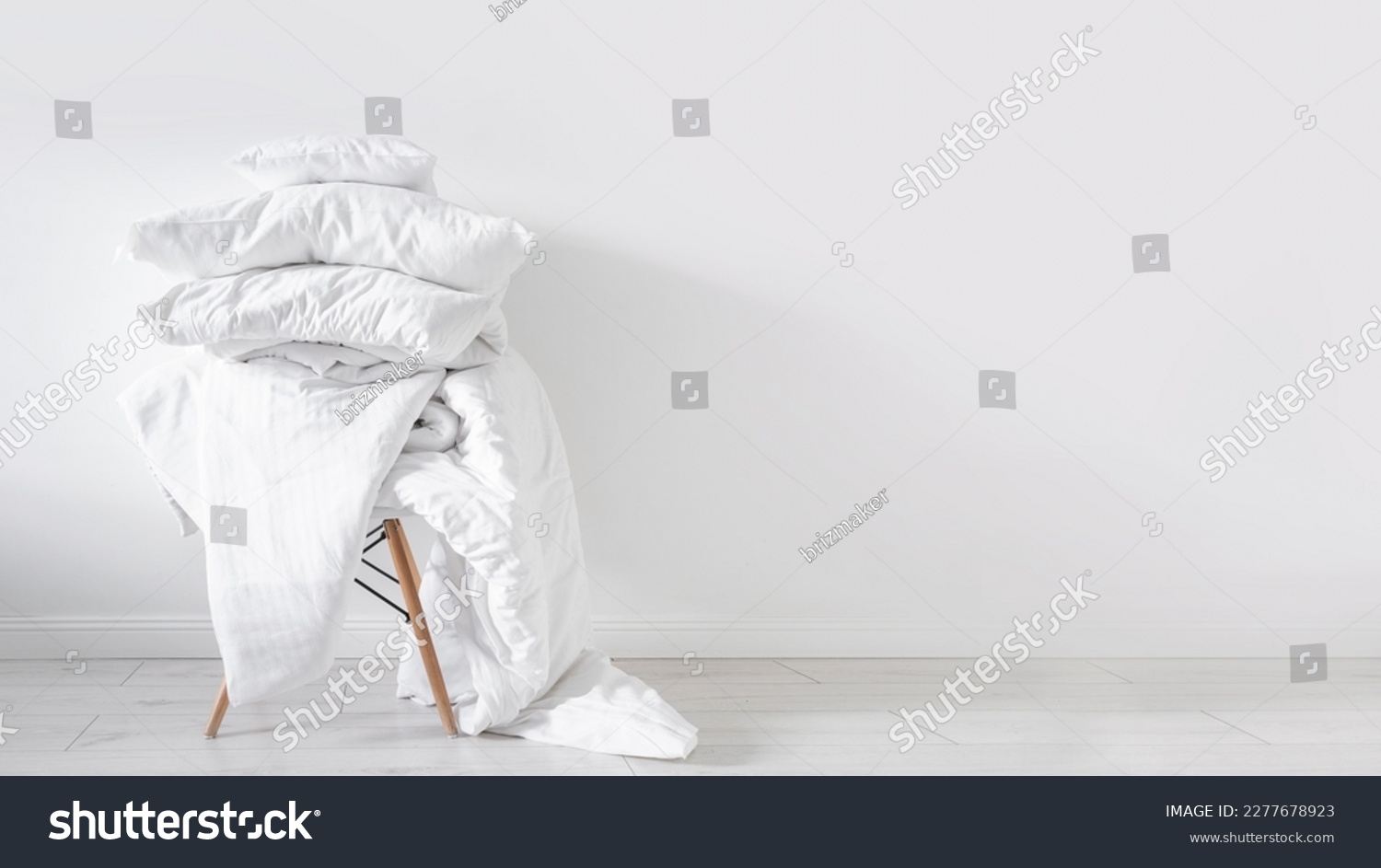 dirty blanket, linen bedding, cotton sheets, cushions and duvet with natural material on chair on white wall background with copy space, washing concept  #2277678923