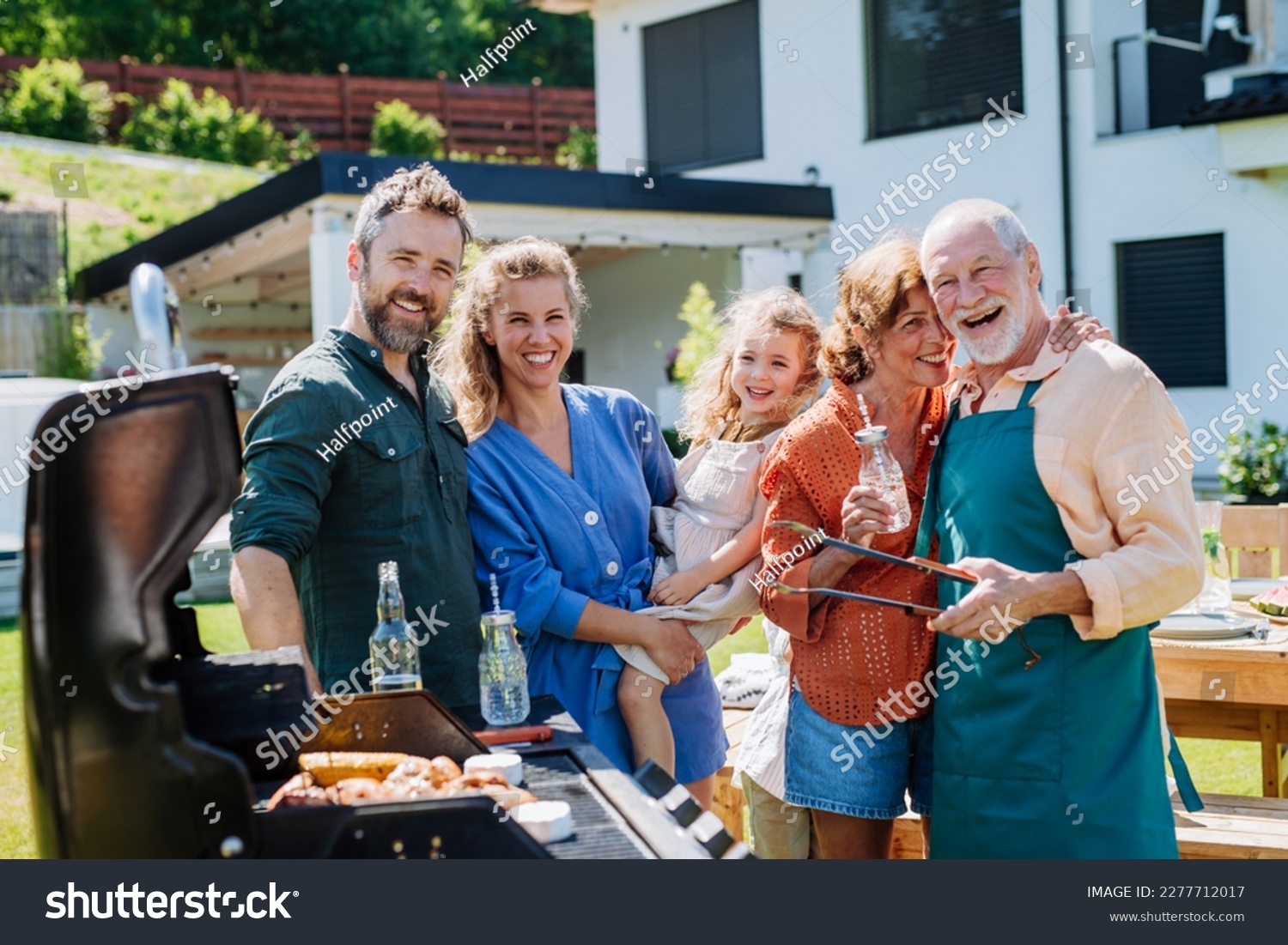 Multi generation family grilling outside on backyard in summer during garden party #2277712017