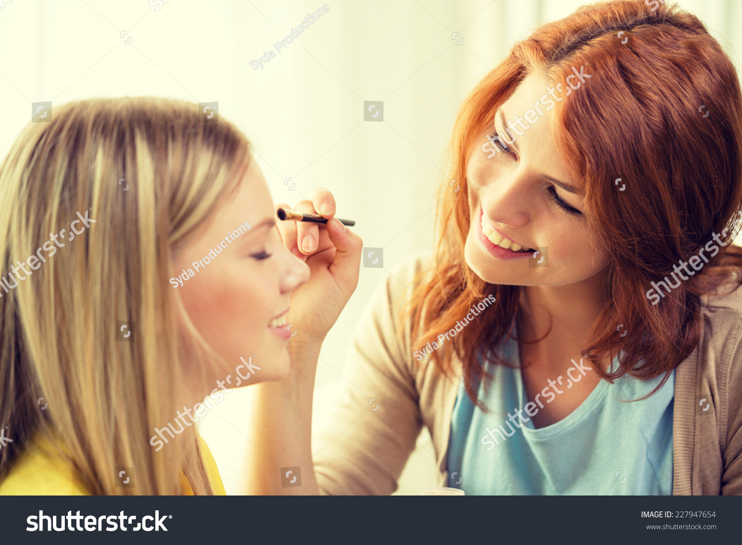 makeup, friendship and leisure concept - two smiling teenage girls applying make up at home #227947654