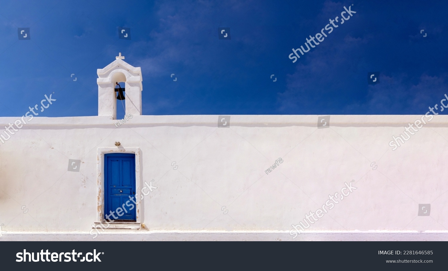Cyclades, Greece. Small white church wall and belfry against blue sky, sunny day. Copy space #2281646585