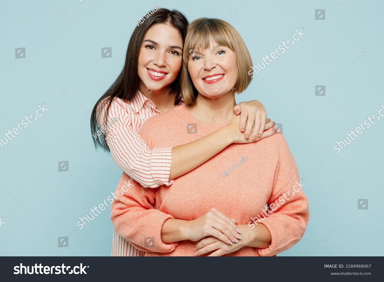 Cheerful lovely fun satisfied elder parent mom with young adult daughter two women together wearing casual clothes hugging cuddle look camera isolated on plain blue cyan background. Family day concept #2284968067