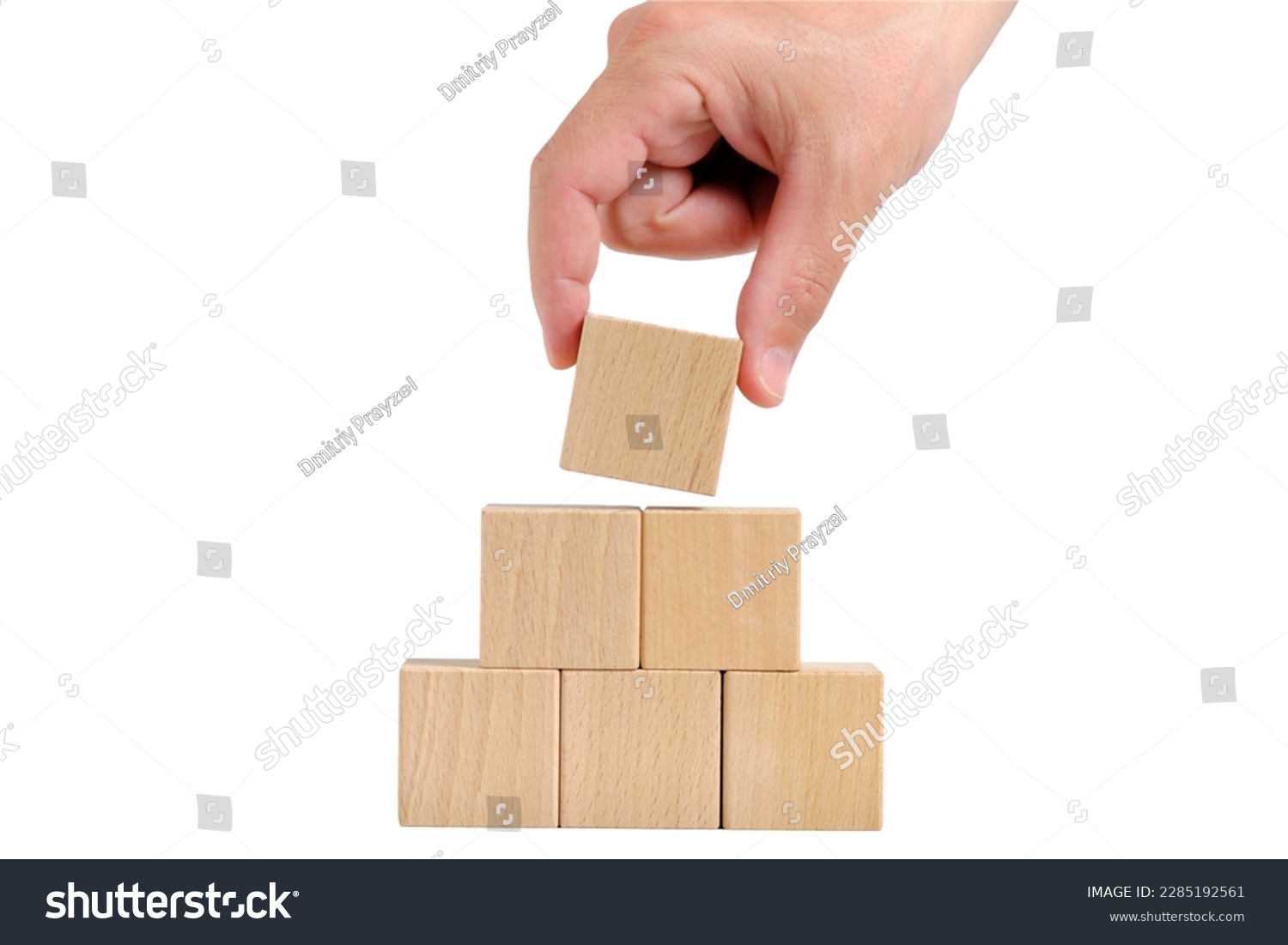 Pyramid of wooden cubes is completed with help hand.Concept of development #2285192561
