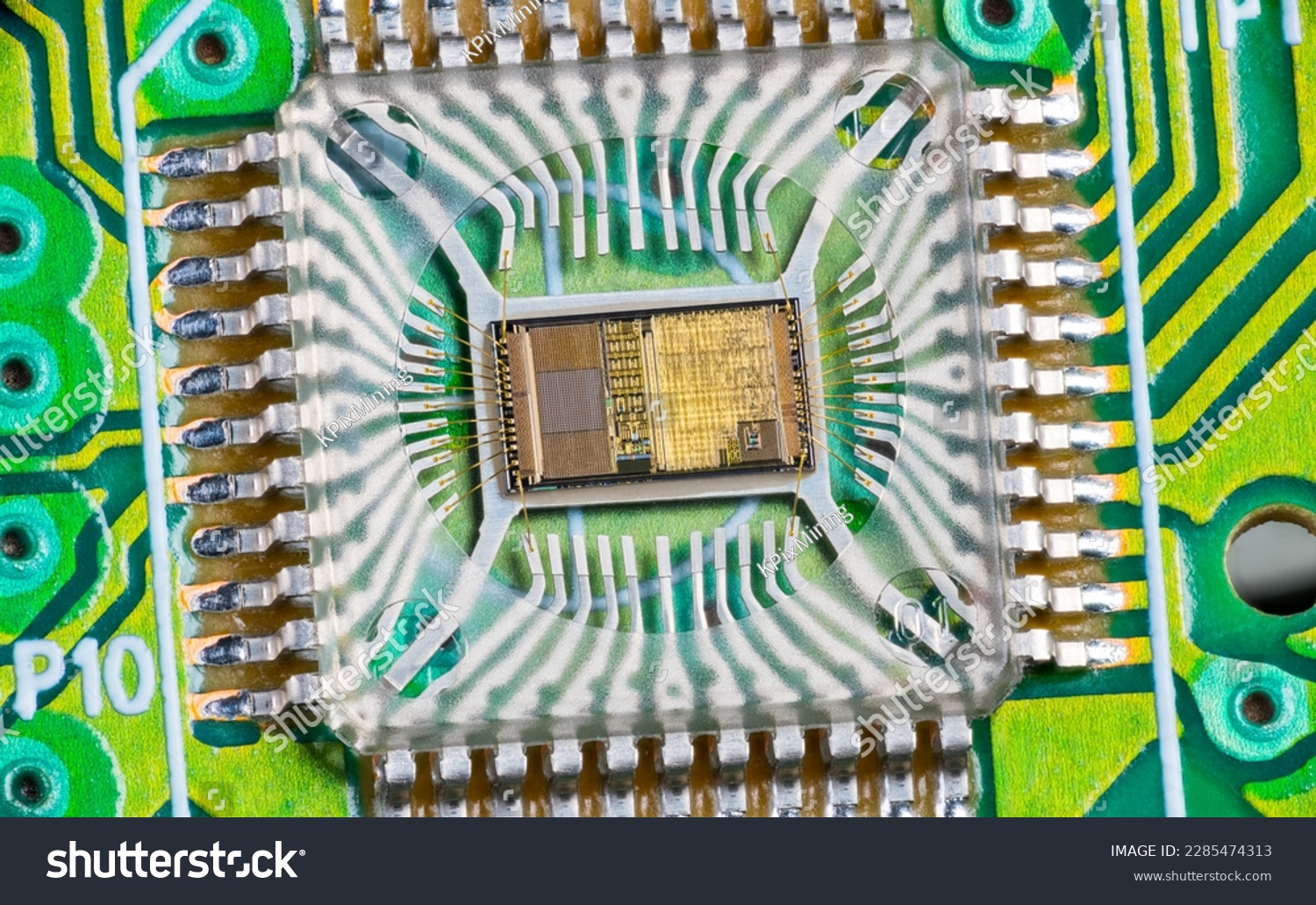 Closeup of electronic integrated circuit die with photodiode array and gold wires on green PCB. Micro chip inside optical computer mouse image sensor in plastic package with round hole and metal pins. #2285474313