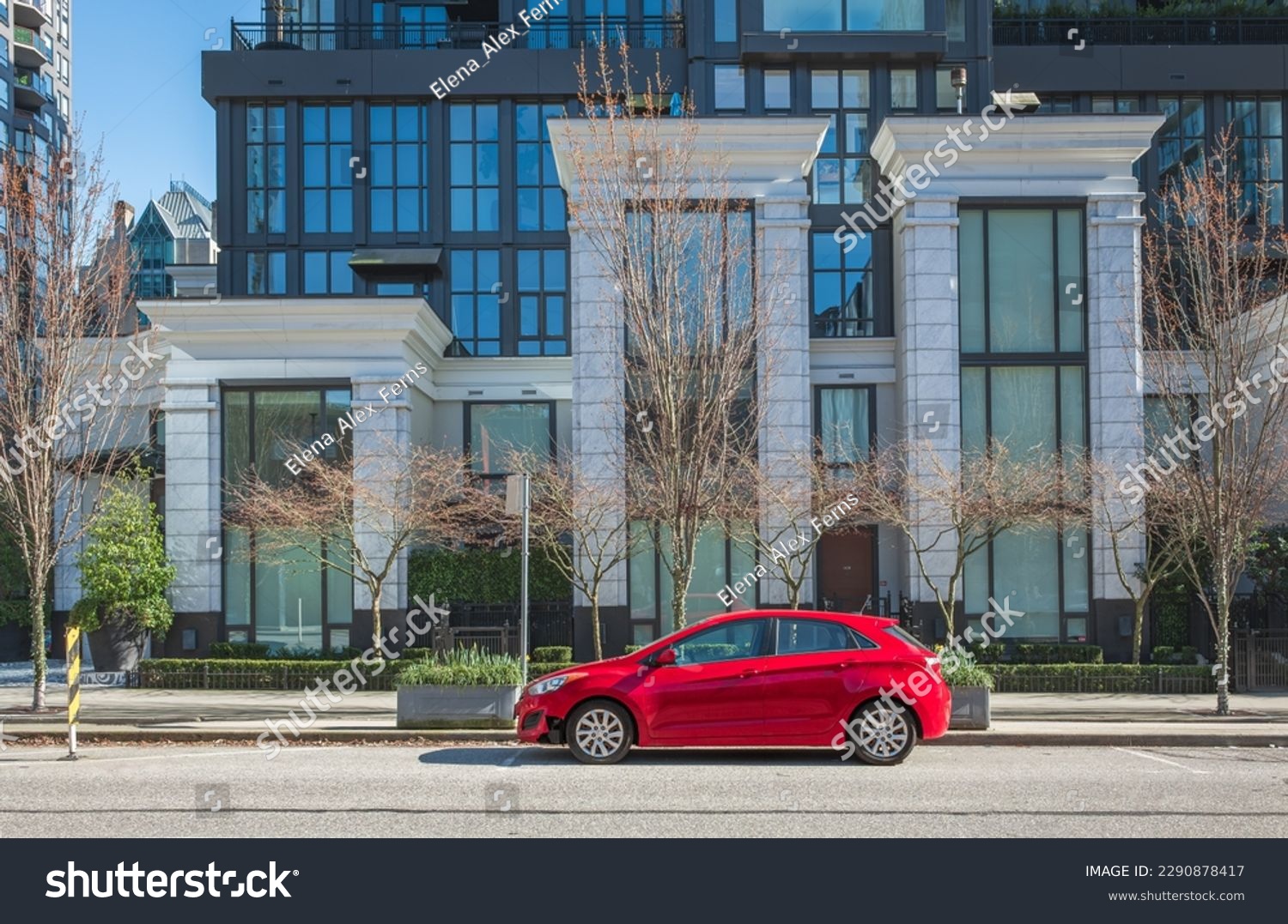 Red car on the empty urban street in a sunny day. Car parked in downtown of Vancouver Canada. Modern architecture view with car parked on a street. Nobody, street photo #2290878417
