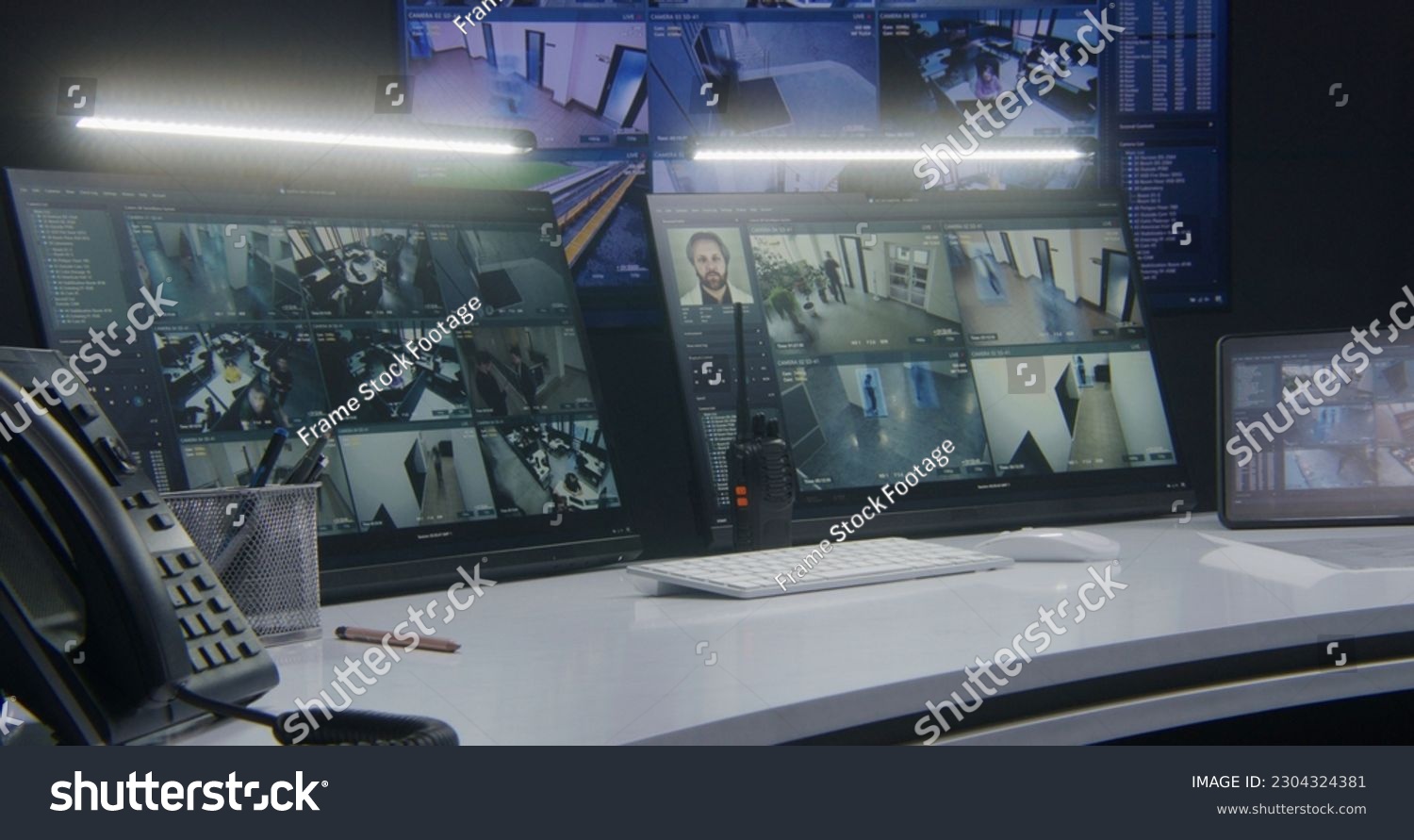 Computer monitors and tablet showing video footage of surveillance cameras with AI facial recognition system. Big digital screen on the wall on background. Modern security control center. Timelapse. #2304324381