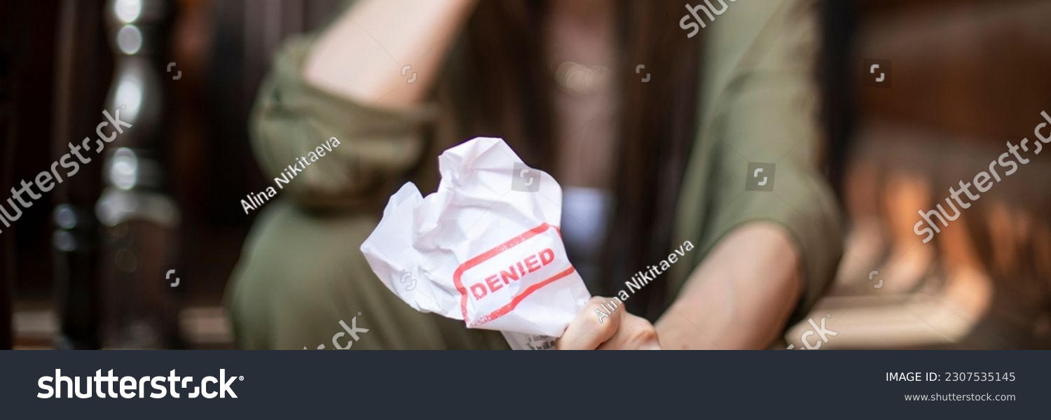 Young brunette long hair girl cries hysterically after being denied a mortgage loan. Depressive sad eviction female millenial holding rejection document copy space banner #2307535145