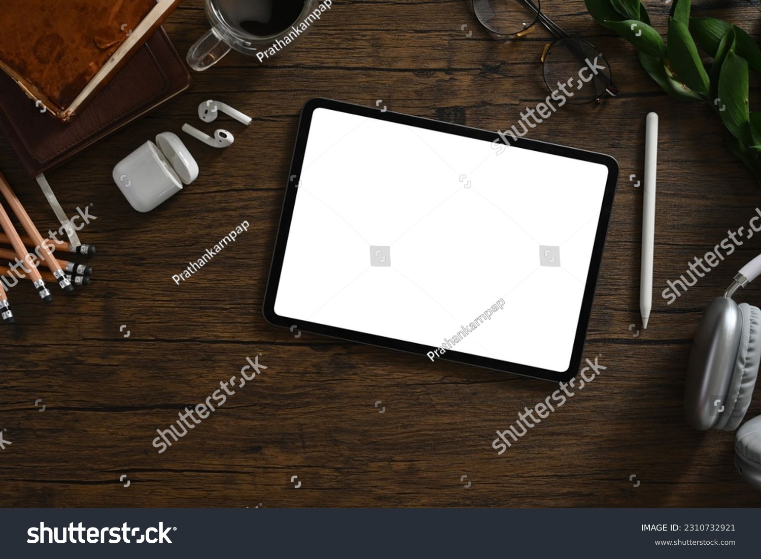 Digital tablet, headphone and stationery on wooden table. Blank screen for your advertising text message #2310732921