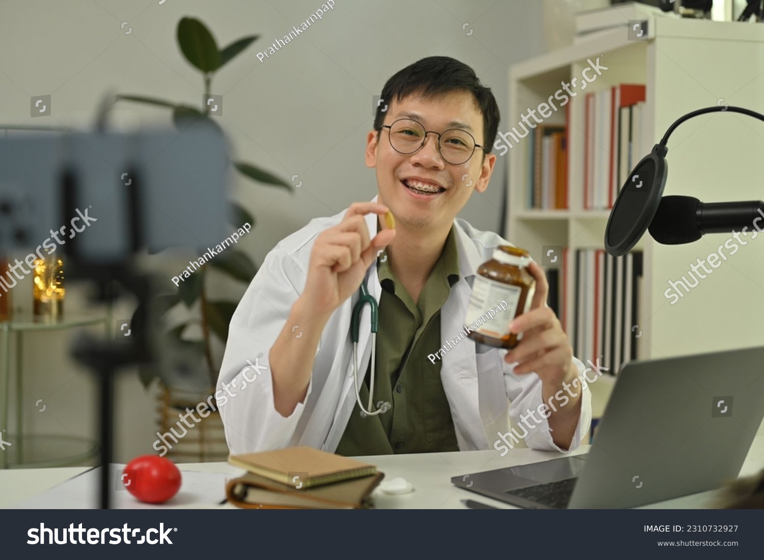 Doctor using microphone and laptop to recording audio about medication advise. Healthcare, medicine and blogging concept #2310732927