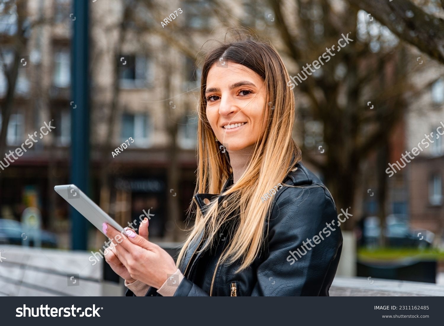 Young hipster girl holding pc tablet in the city.Traveler woman using tablet.reading guide book map on tablet computer pc,using mobile internet.Female writes text message or content. #2311162485