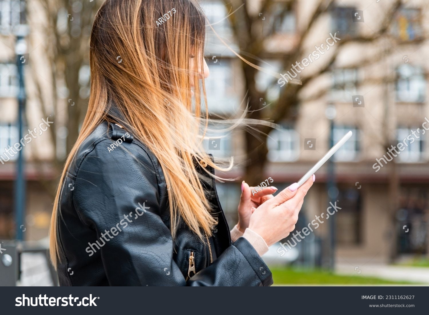 Young hipster girl holding pc tablet in the city.Traveler woman using tablet.reading guide book map on tablet computer pc,using mobile internet.Female writes text message or content. #2311162627