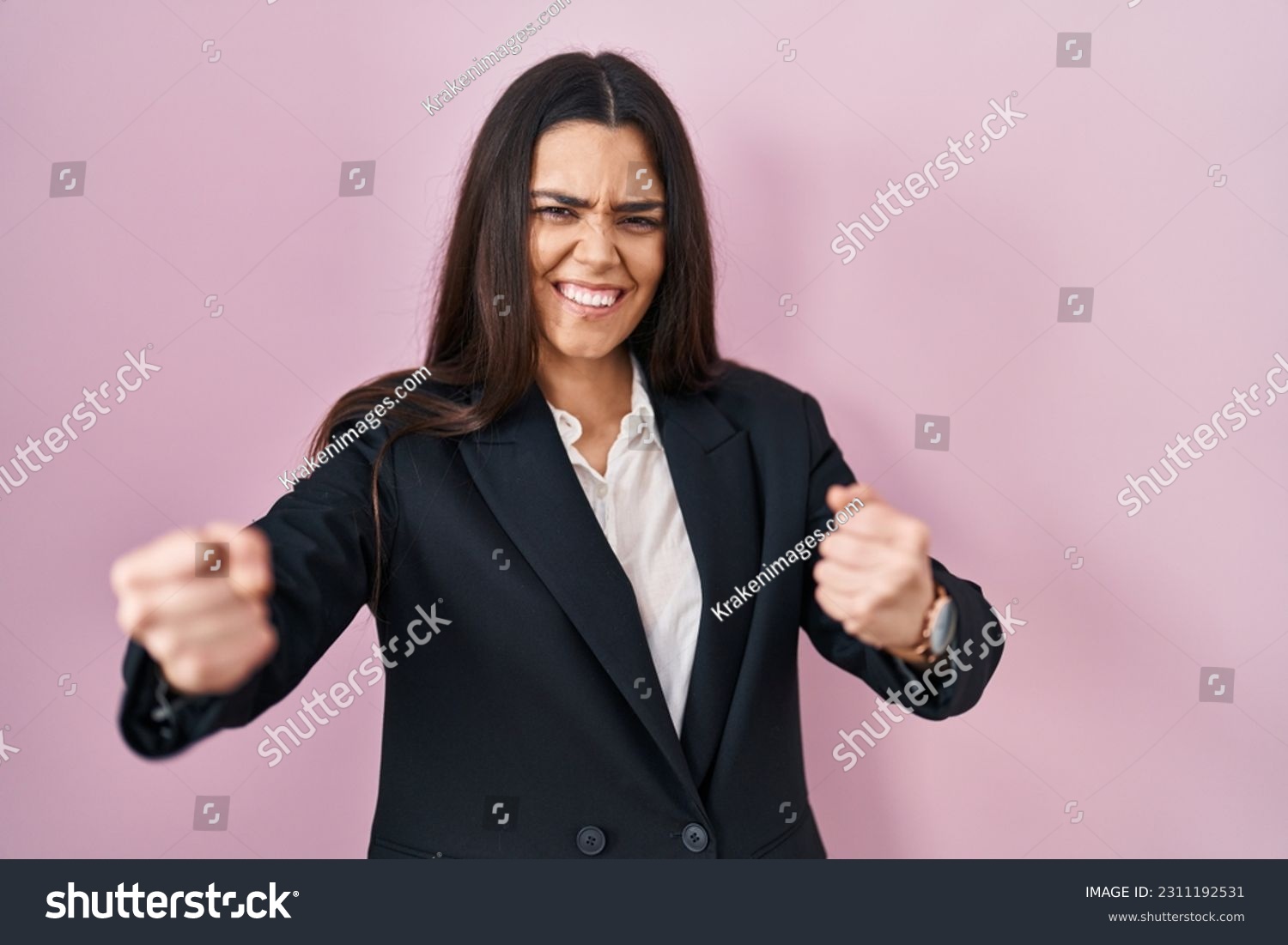 Young brunette woman wearing business style over pink background angry and mad raising fists frustrated and furious while shouting with anger. rage and aggressive concept.  #2311192531
