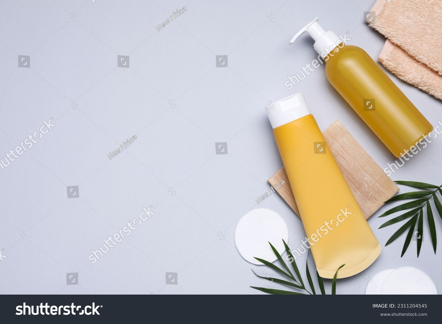 Different cleansers, leaves, and cotton pads on light grey background, flat lay with space for text. Cosmetic product #2311204545