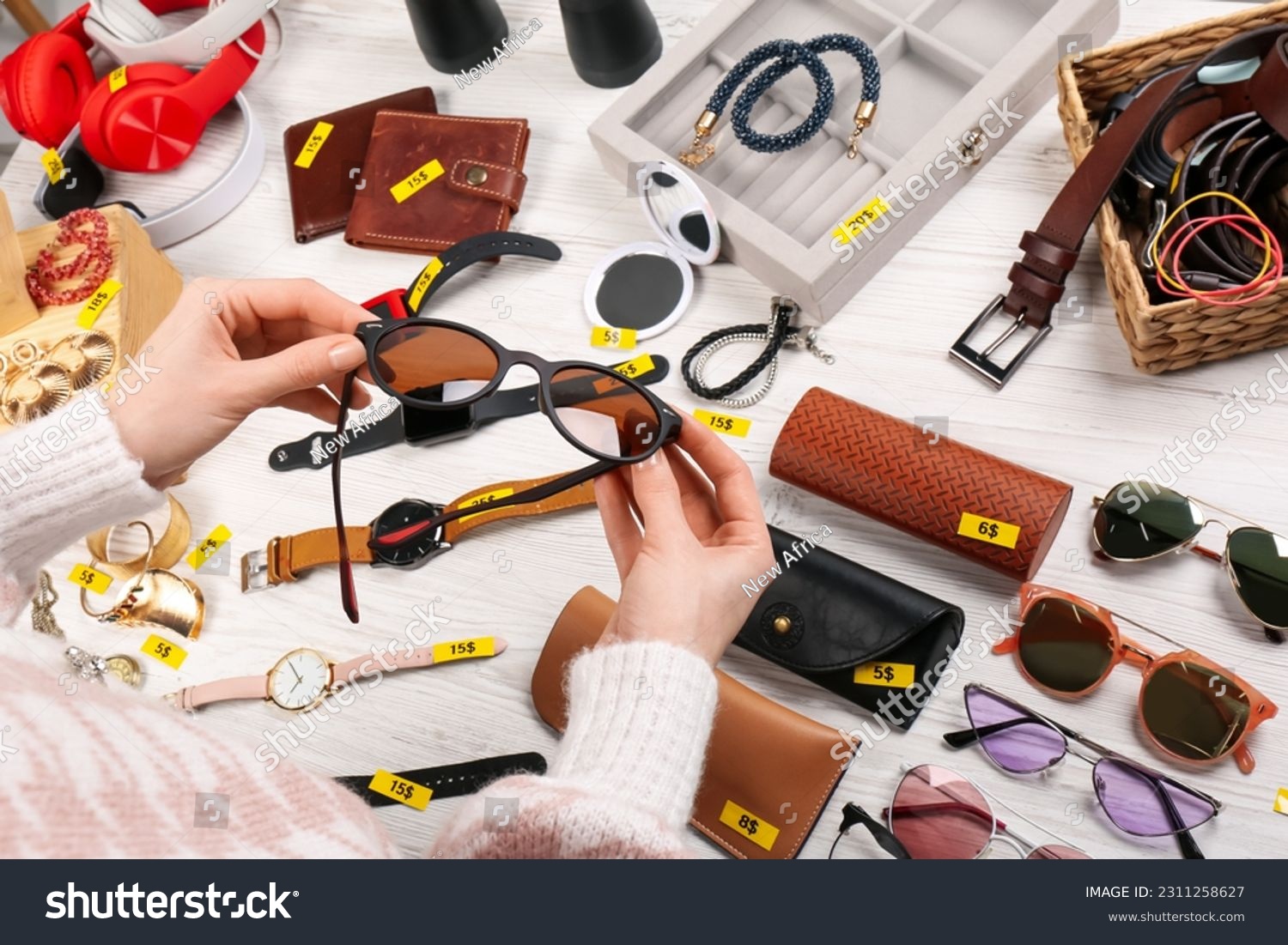Woman holding glasses near table with different stuff, closeup. Garage sale #2311258627