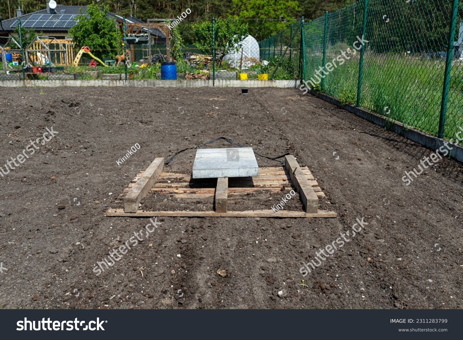 Leveling the chernozem in the yard with a pallet weighted with a concrete cube, preparing for sowing the lawn. #2311283799