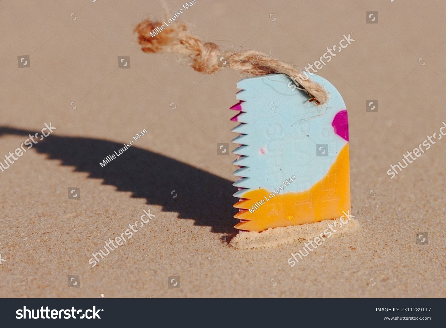 Surfboard wax comb on the sand #2311289117
