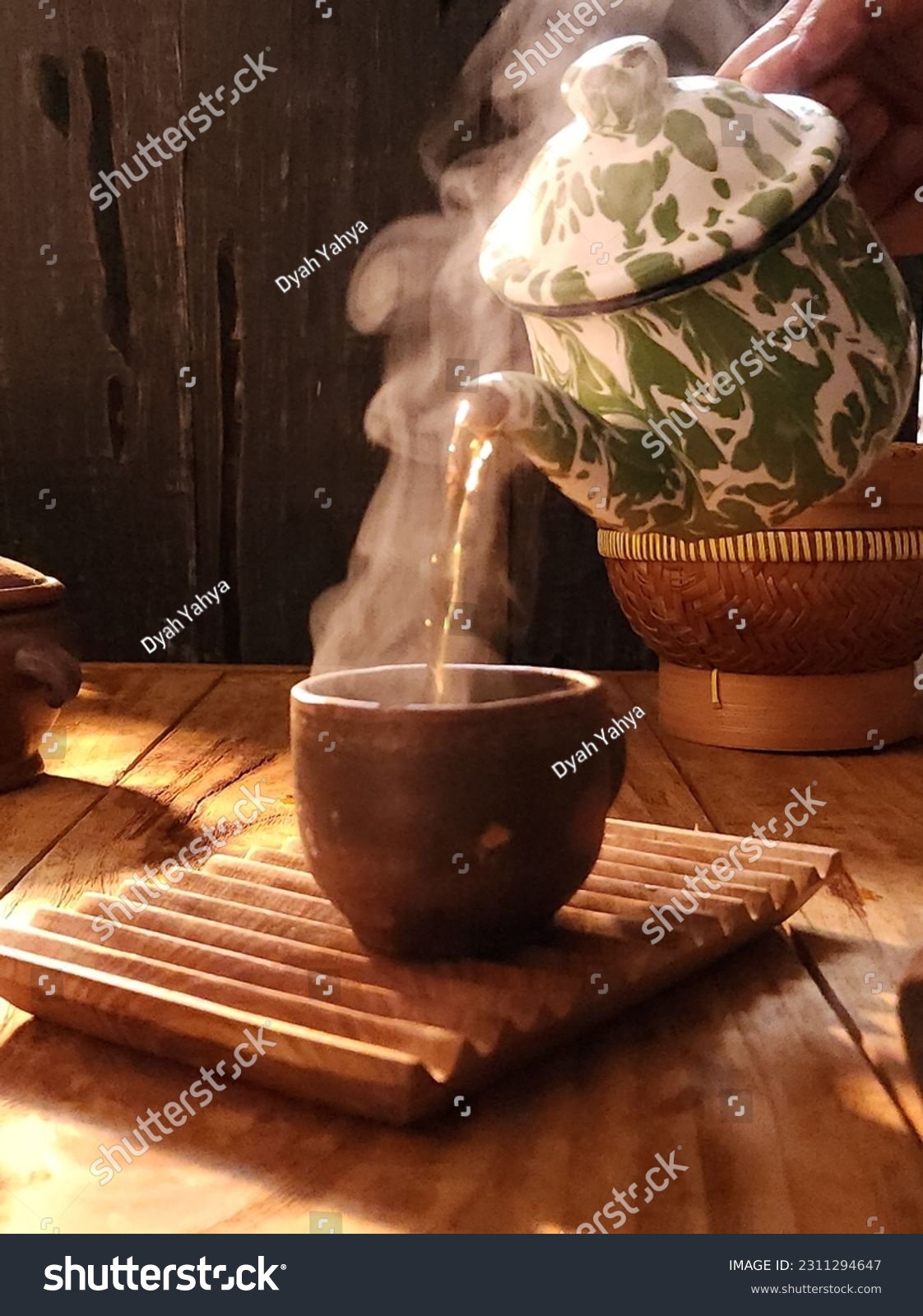 hot steam from a teapot pouring into an earthenware glass

 #2311294647