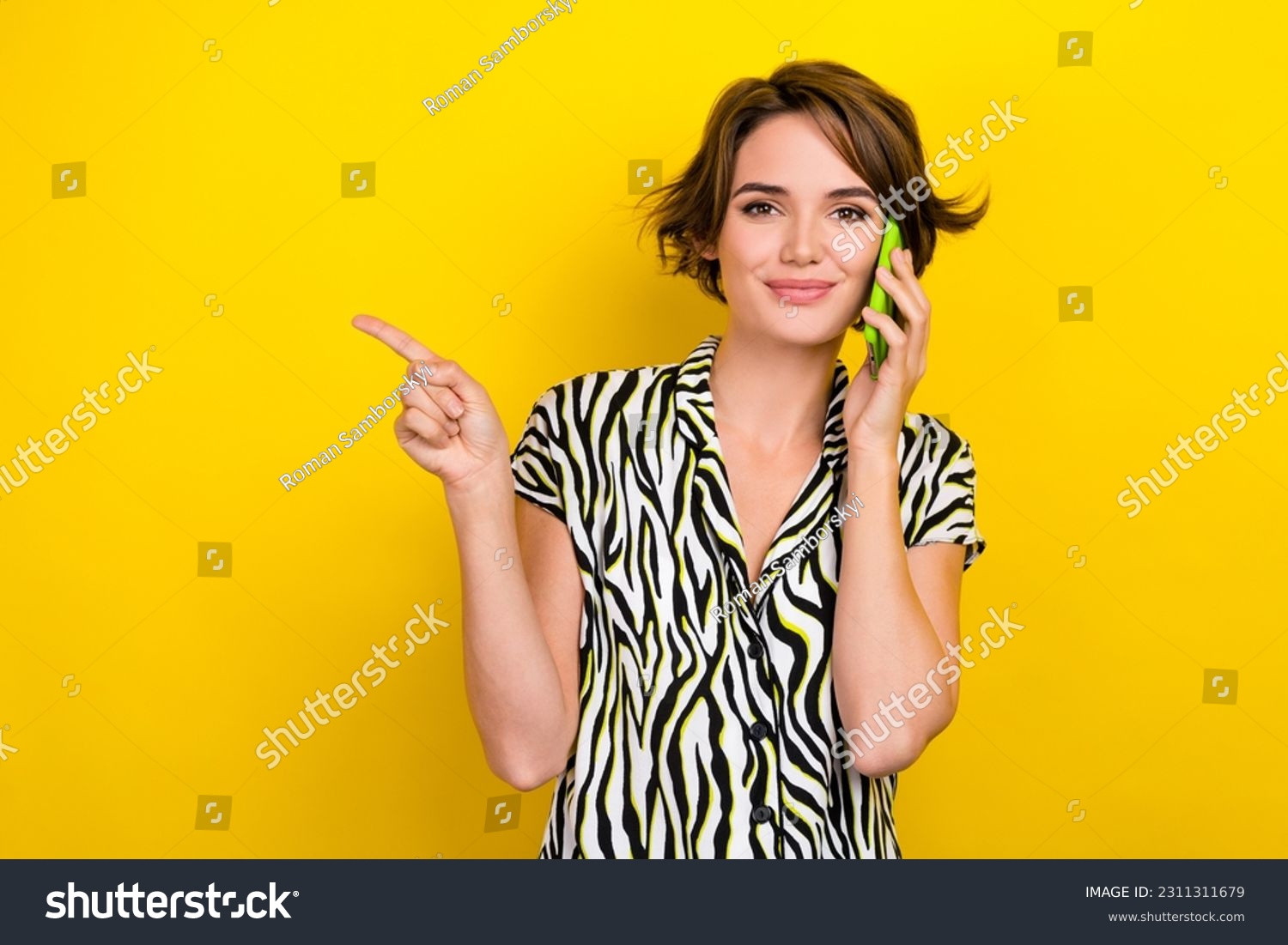 Portrait of positive cheerful woman wear striped blouse talk on phone directing at sale empty space isolated on yellow color background #2311311679