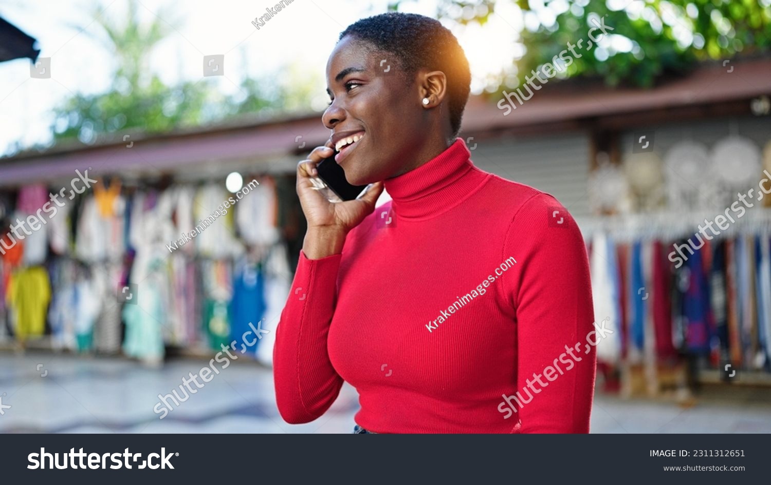 African american woman talking on smartphone smiling at street market #2311312651