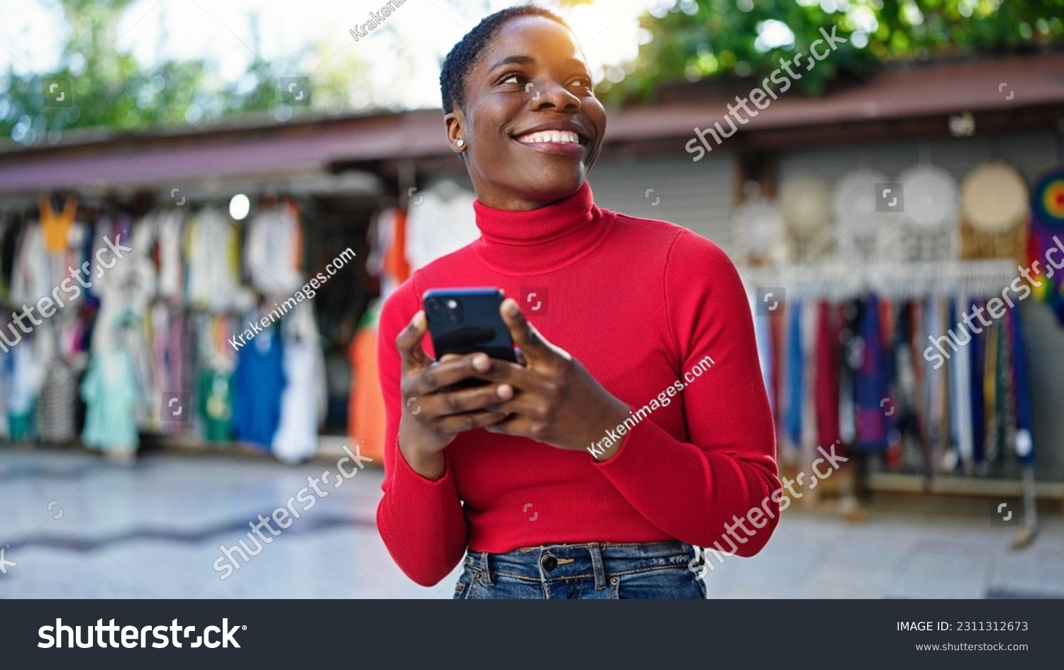 African american woman using smartphone smiling at street market #2311312673