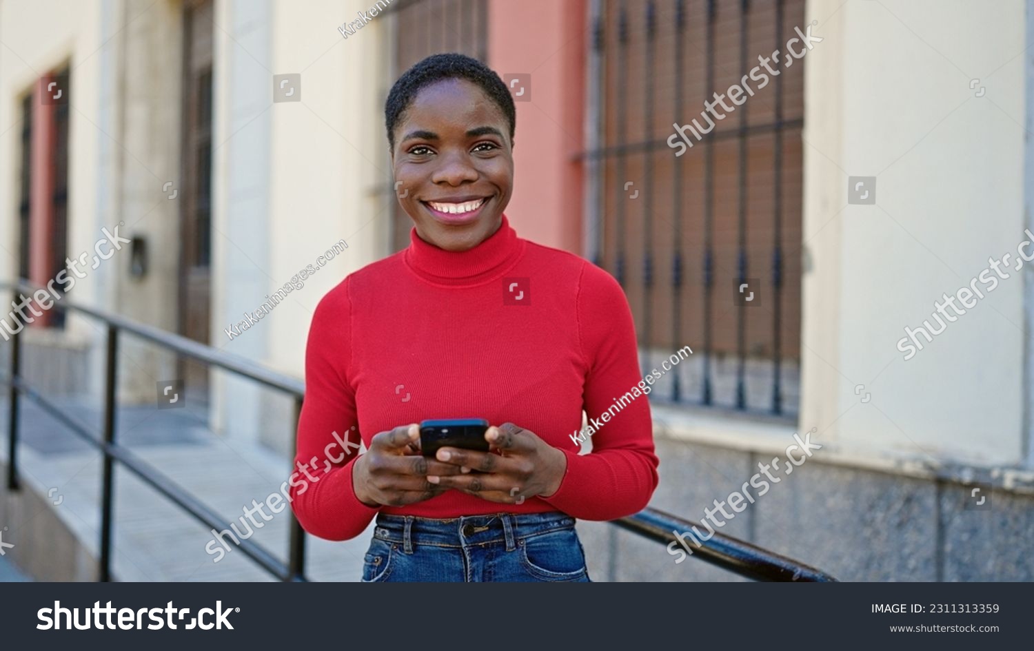 African american woman using smartphone smiling at street #2311313359