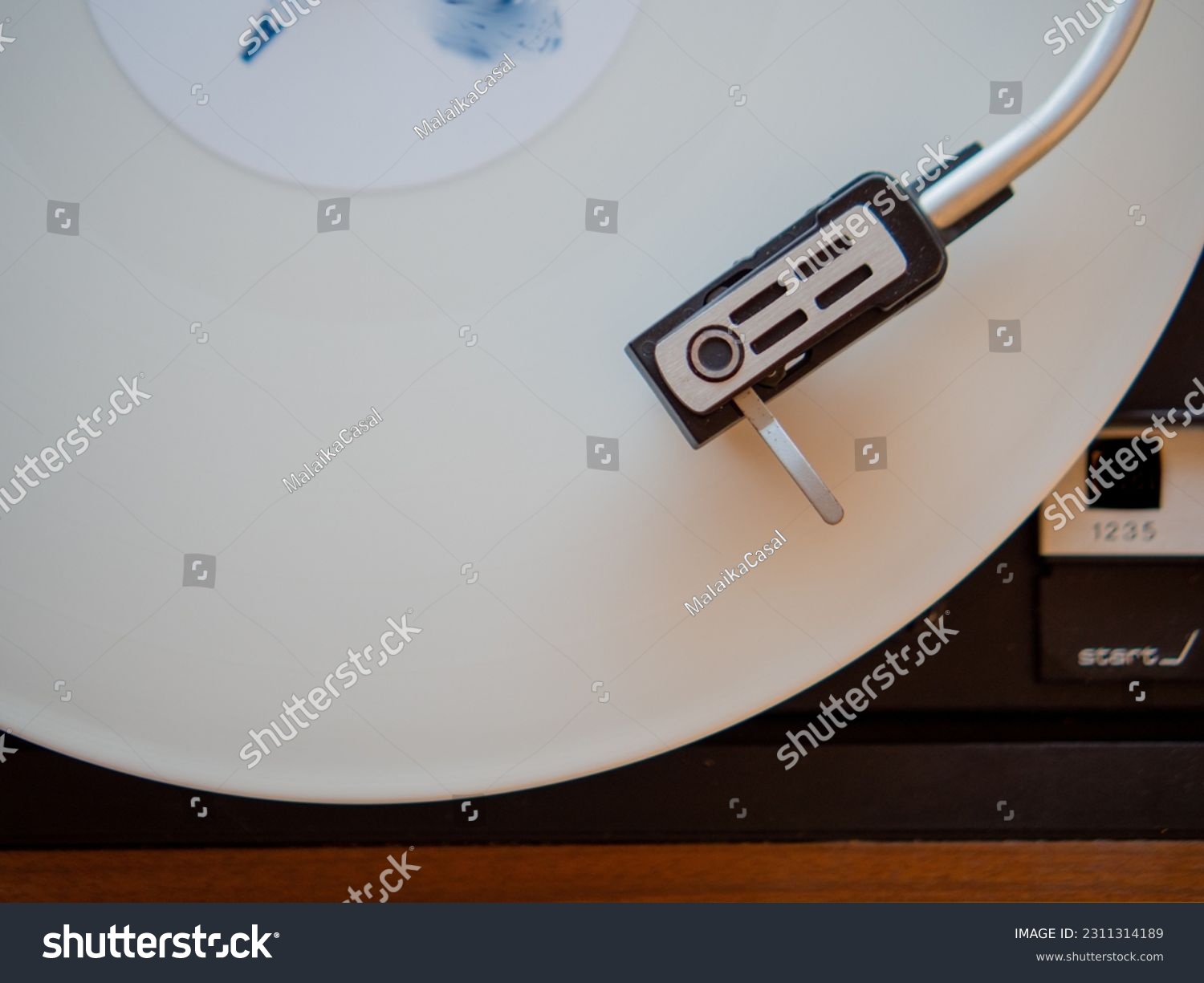 Detail of a needle on a track of a white vinyl record. Vintage turntable. #2311314189