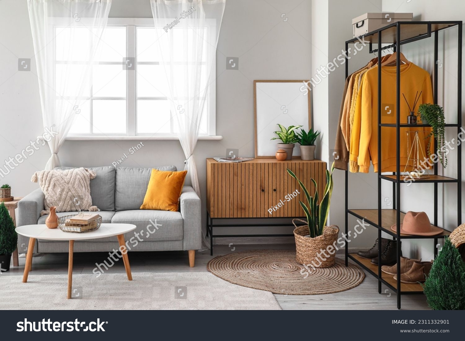 Interior of living room with shelving unit, clothes and sofa #2311332901