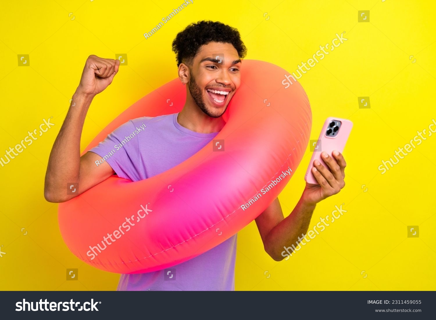 Portrait of excited crazy guy hold inflatable circle buoy raise fist success use smart phone isolated on yellow color background #2311459055