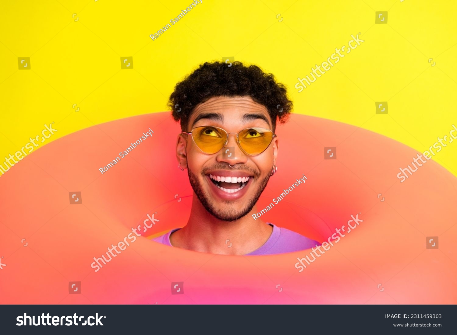 Portrait of funky positive handsome man head through inflatable ring hole look up empty space isolated on yellow color background #2311459303