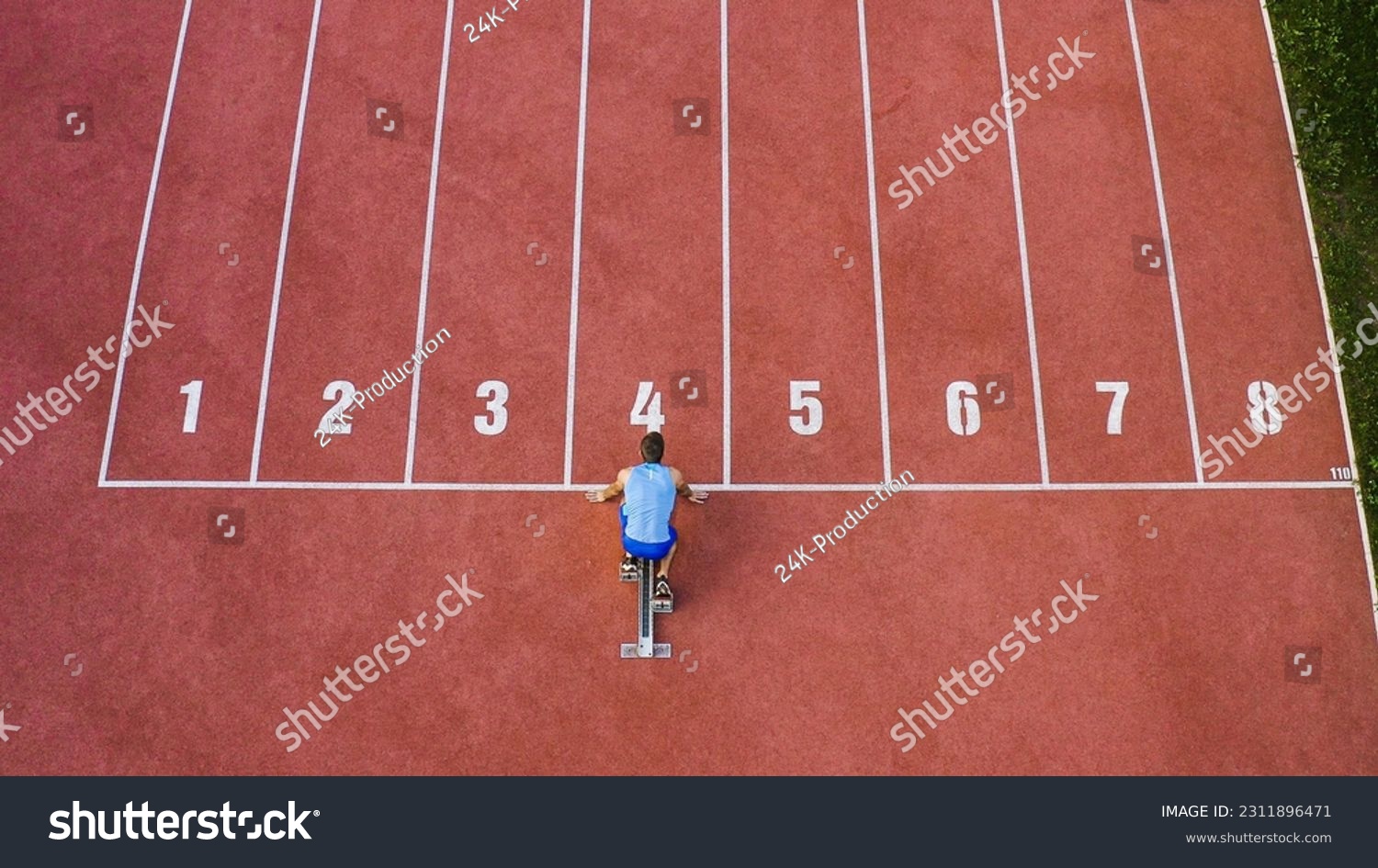 Caucasian male sprint runner alone on the athletic track, taking starting position and running in line four, aerial above shot. #2311896471