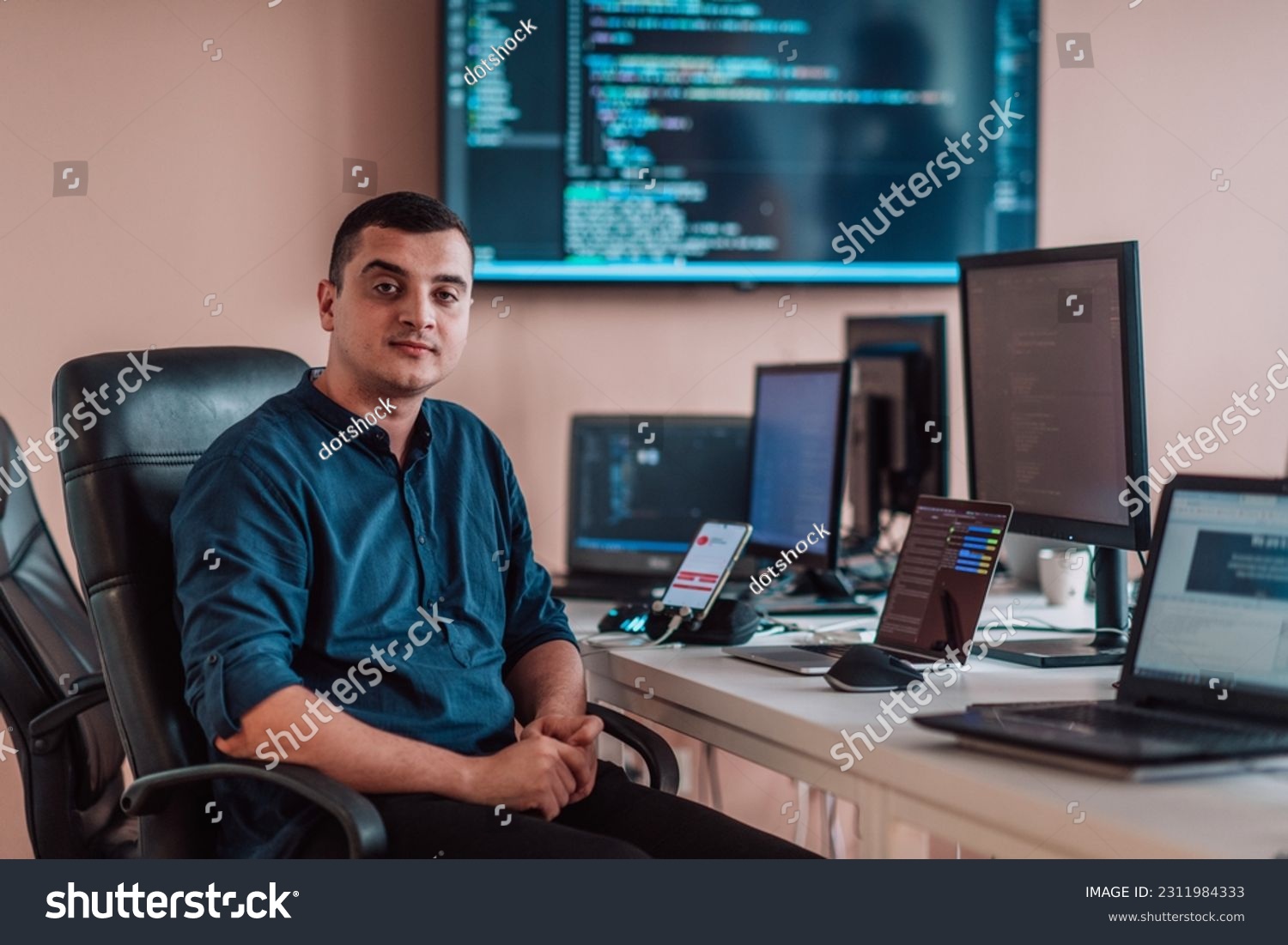 A programmer diligently testing smartphone applications while sitting in their office. #2311984333