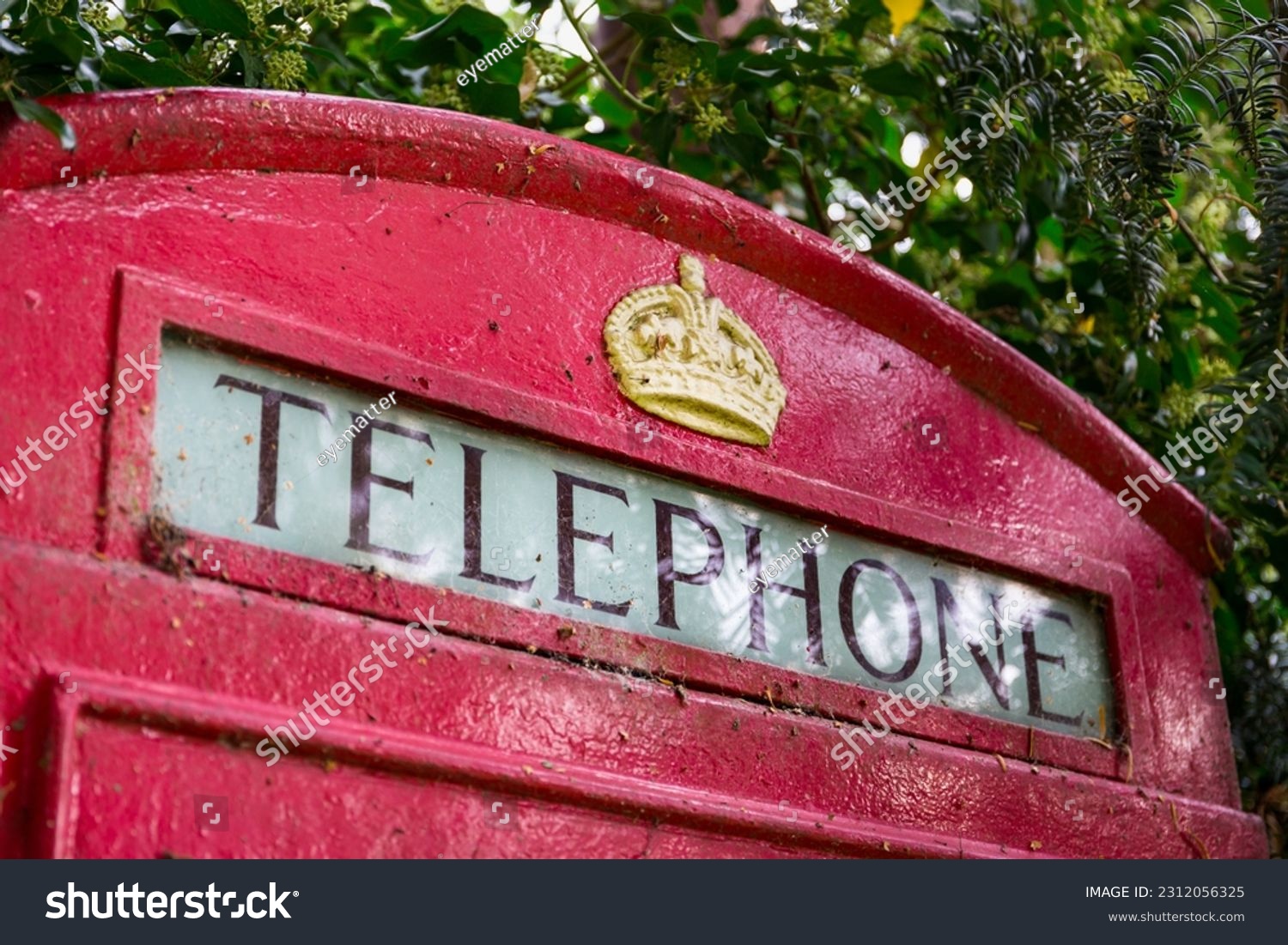 Sign at the top of a classic red British telephone box, featuring a gold crown #2312056325