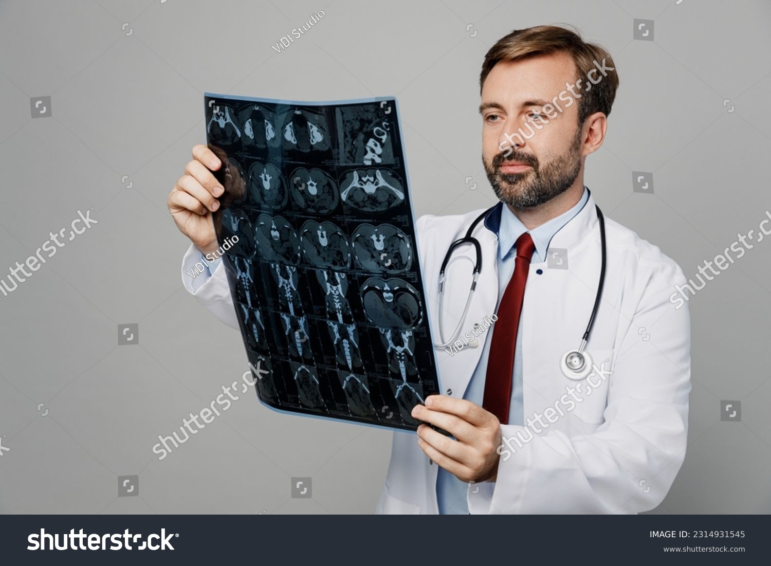 Male doctor man wears white medical gown suit work in hospital hold x-ray radiographic image ct scan head brain mri isolated on plain grey color background studio portrait. Healthcare medicine concept #2314931545