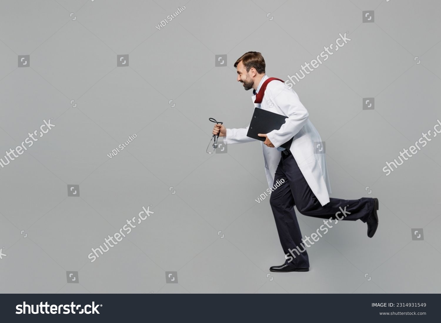 Full body side view male doctor man wears white medical gown suit work in hospital hold clipboard with paper documents run isolated on plain grey color background studio Healthcare medicine concept #2314931549