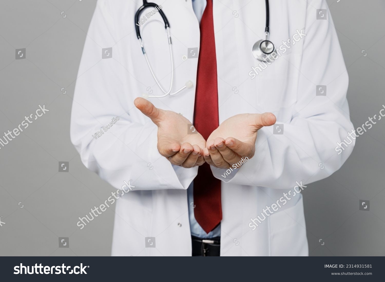 Cropped male doctor happy man wearing white medical gown suit work in hospital hold hands show empty palms offer something isolated on plain grey color background studio. Healthcare medicine concept #2314931581