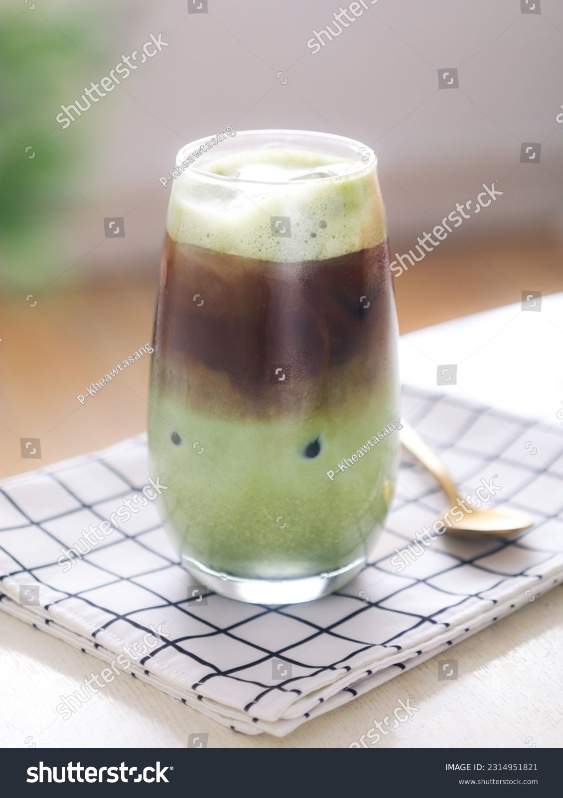 A clear glass of mixed iced matcha green tea and espresso latte. It's a trendy beautifully layered drink of matcha espresso with milk #2314951821