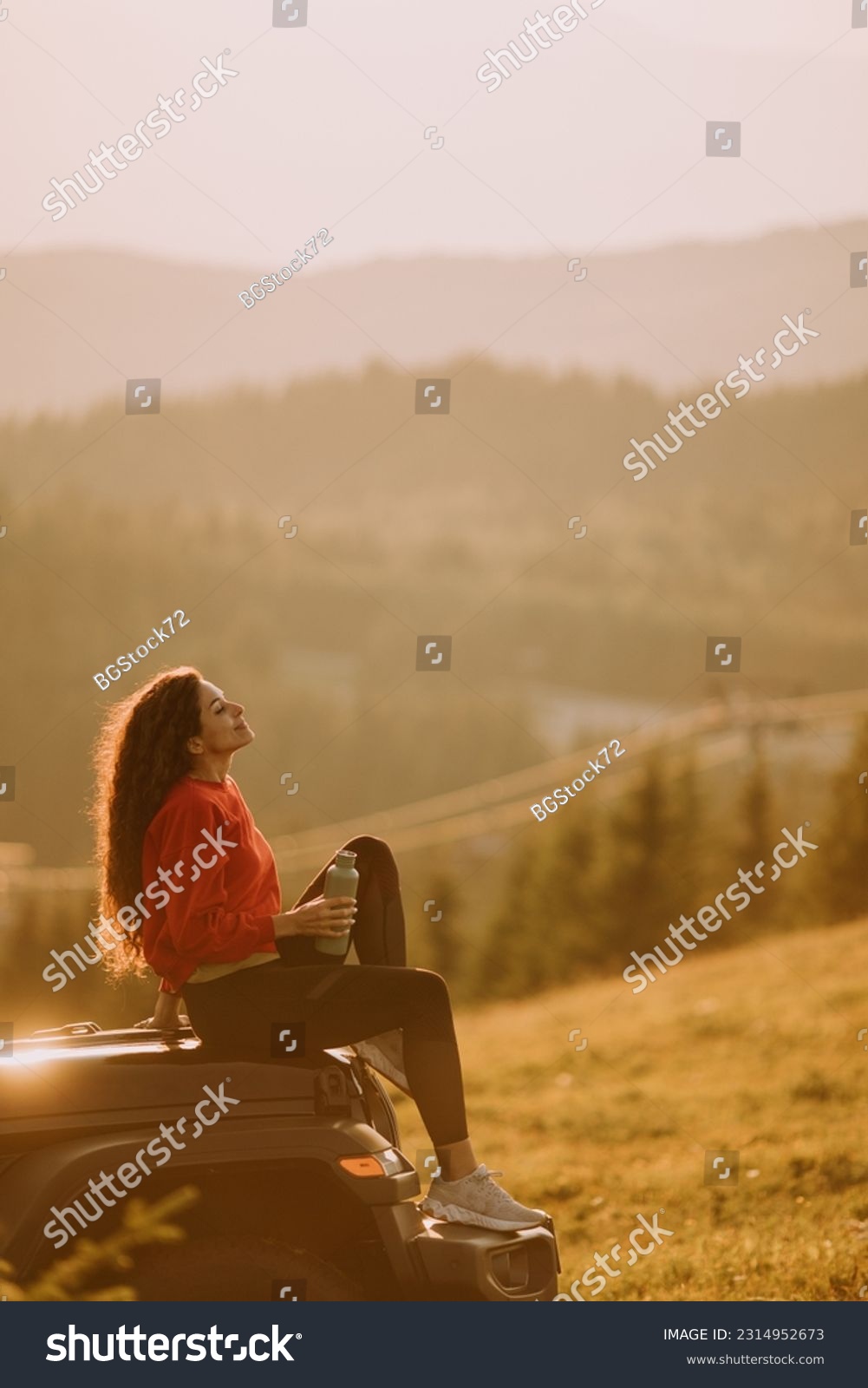 Pretty young woman relaxing on a terrain vehicle hood at countryside #2314952673