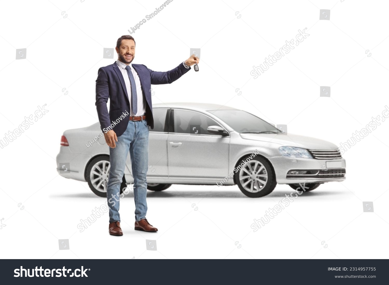 Smiling professional man holding a car key in front of a sliver car isolated on white background #2314957755