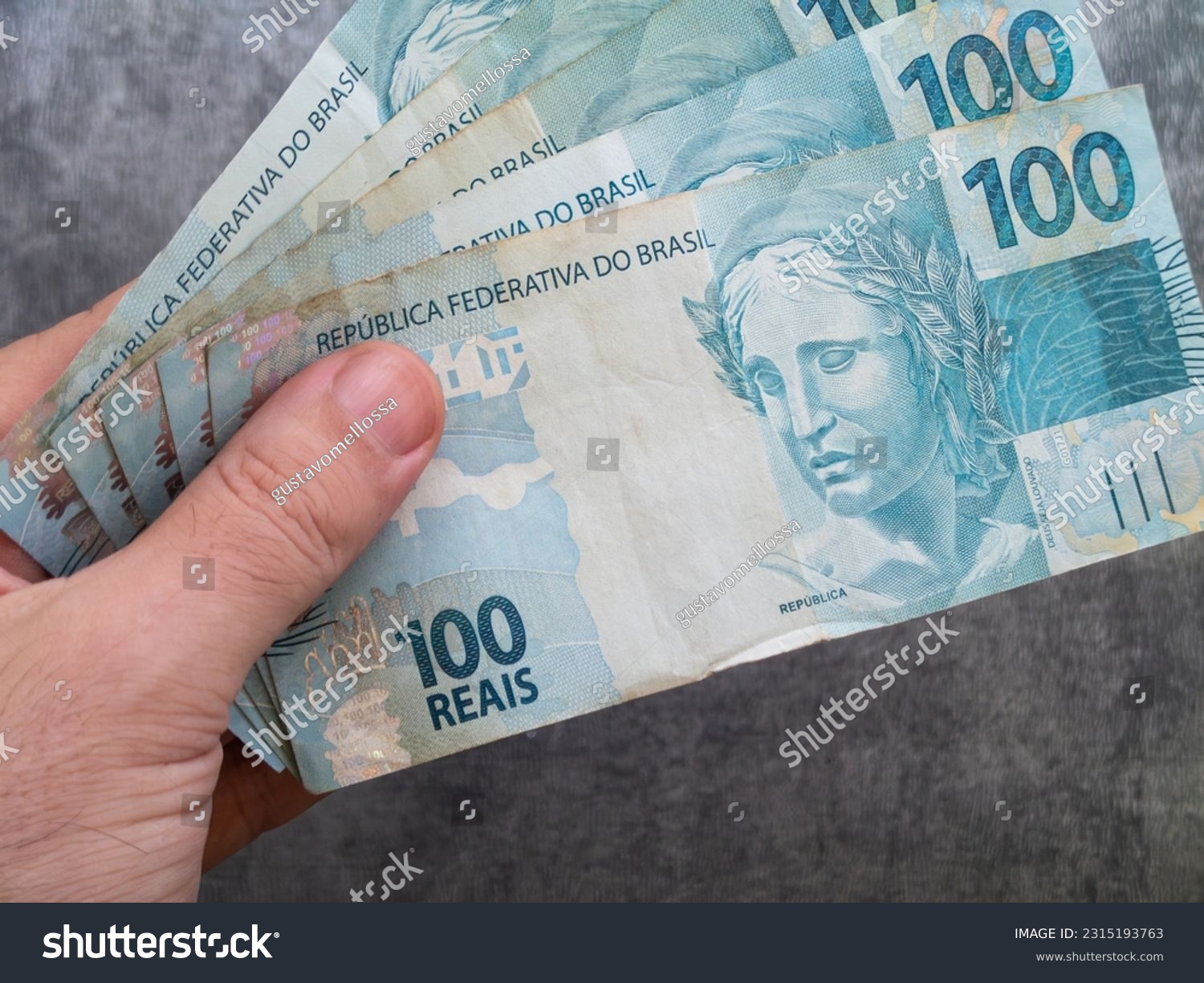 Hand holding Brazilian one hundred reais banknotes. Finance concept. #2315193763